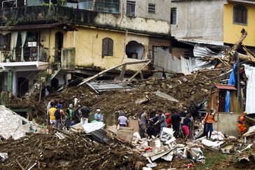 Bombeiros, moradores e voluntários trabalham no local do deslizamento no Morro da Oficina, após a chuva que castigou Petrópolis, na região serrana fluminense