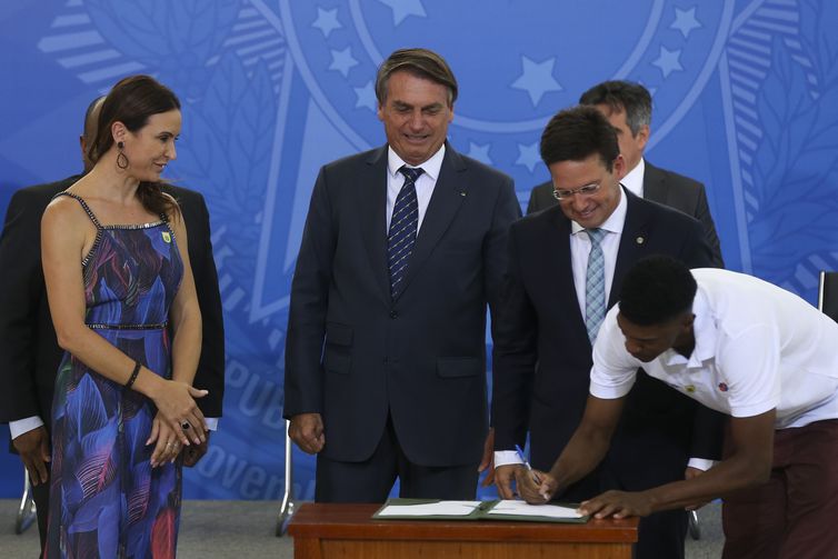 A atleta Maurren Maggi, o presidente da República, Jair Bolsonaro, o ministro da Cidadania, João Roma, e o atleta, André Domingos, participam da solenidade de assinatura do projeto de lei que institui o Plano Nacional do Desporto (PND), no