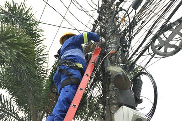 Funcionários da Rioluz trabalham na retirada de fios em Benfica, zona norte da cidade. Prefeitura lança programa Caça-Fios, uma força-tarefa para eliminar fiações que ficam soltas, partidas e caídas nas vias da cidade.